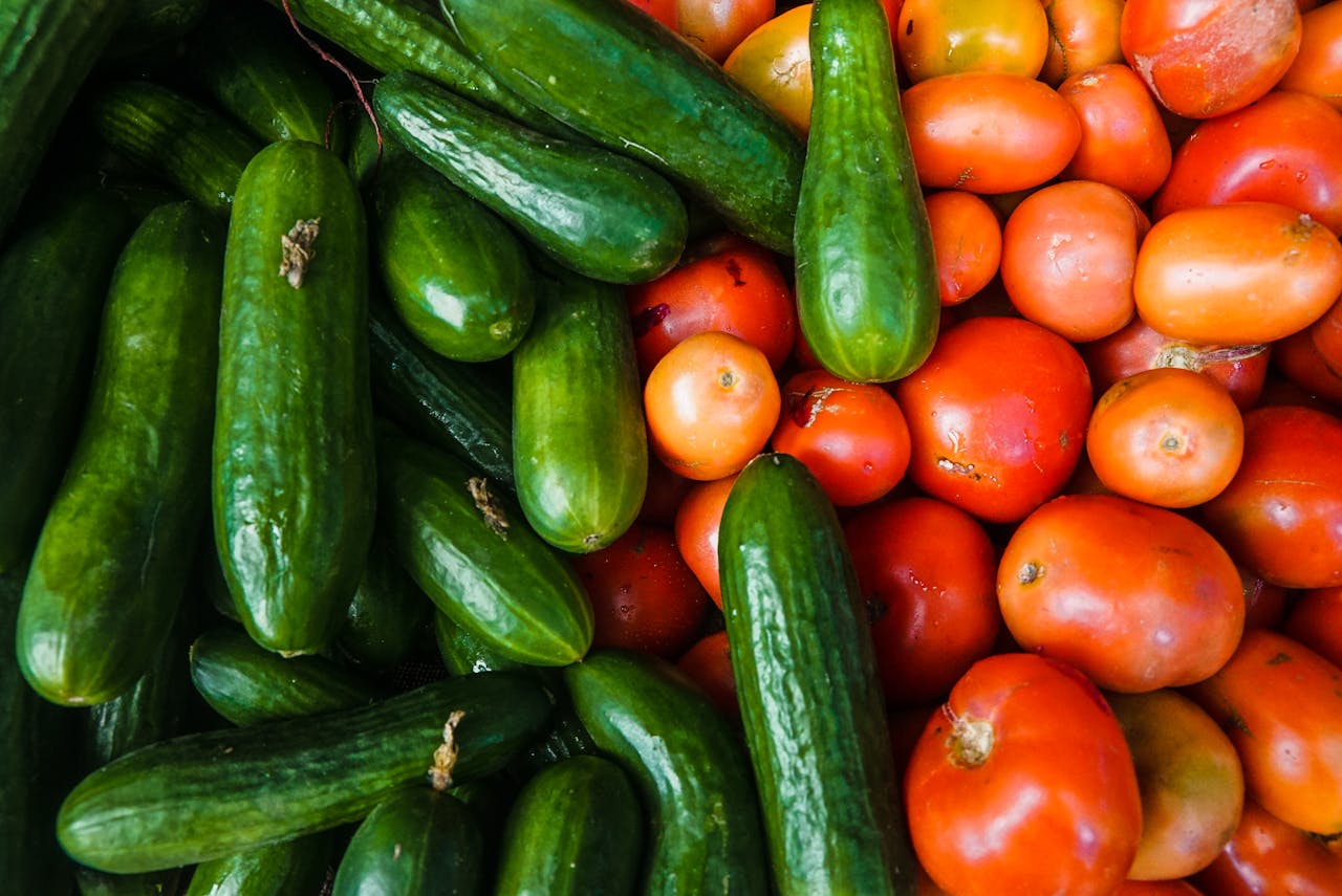 A vibrant display of juicy cucumbers and ripe tomatoes at a local market.